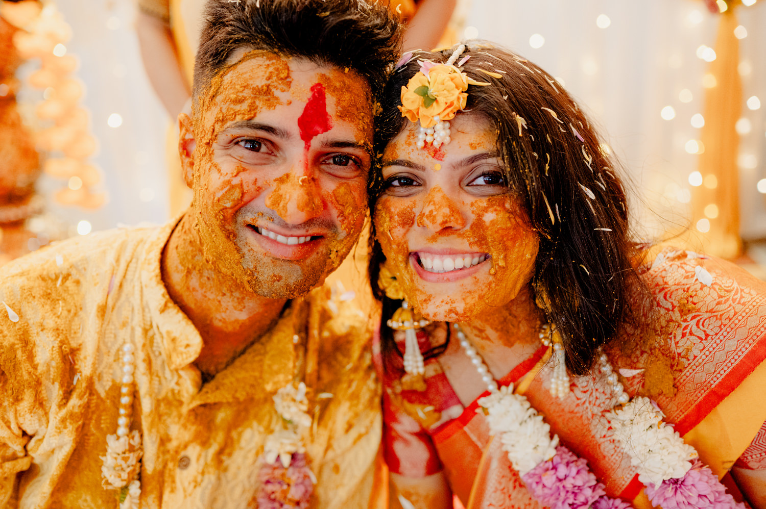 A smiling Indian couple covered in turmeric paste for their Haldi ceremony