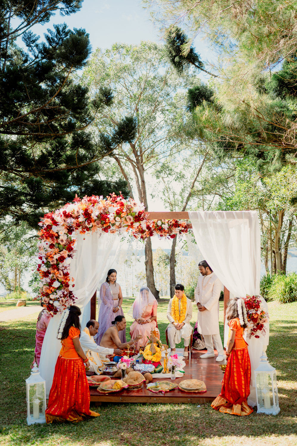 A traditional Indian wedding ceremony on a mandap held outdoors under trees